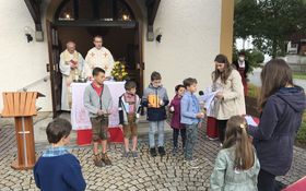 Kinder stehen vor der Michaelskapelle, im Hintergrund Pfarrer Bayer und Pfarrer Fenk