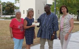 3 Frauen überreichen einem Pfarrer aus Burkina Faso einen Scheck