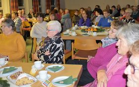 Senioren sitzen um weihnachtlich eingedeckte Kaffeetafel
