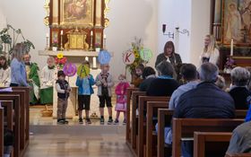 Kinder vor einem Altar, die runde Schilder mit den Buchstaben D A N K E hoch halten