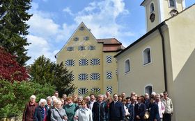 Gruppenbild von erwachsenen Menschen vor einem historischen Schloss