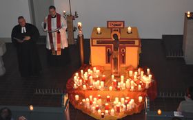viele Kerzen auf gelb/roten Tüchern im Hintergrund Pfarrer Fenk und Pfarrer Berthold