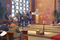 ein Kinderchor mit zwei Erwachsenen als Leiterinnen, die Gitarre spielen