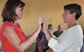 zwei Frauen stehen sich gegenüber und legen die Hände aneinander