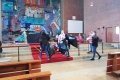 Kinder tragen schwarze Müllsäcke vor den Altar der Friedenskirche
