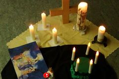 Holzkreuz und diverse brennende Kerzen stehend auf einem gelben Tuch, daneben liegt ein Bild der heiligen Lucia