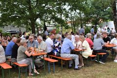 Leute auf Bierbänken unter freiem Himmel
