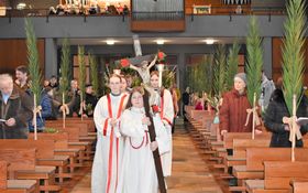 Ministranten ziehen mit einem Kreuz durch den Mittelgang der Friedenskirche Grafenwöhr