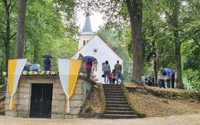 Grotte mit weiß-gelben Fahnen und Blumen geschmückt, im Hintergrund die Annabergkirche in Grafenwöhr