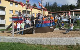 Gruppenbild von Kindern und Erwachsenen auf einem Schiff, das auf einem Spielplatz steht