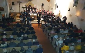 voll besetzter Kircheninnenraum, im Altarraum stehen zwei Chöre