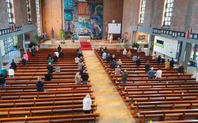 Gläubige stehen in einer Kirche mit viel Abstand