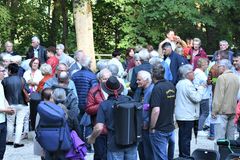 Viele Gläubige stehen beisammen und unterhalten sich bei einem Becher Wein und Wasser