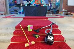 Besen, Eimer, Staubsauger und Lappen liegen auf einem roten Teppich vor dem Altar der Friedenskirche