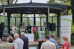 Katholische und evangelische Priester stehen in einem Pavillon im Max-Reger-Park in Weiden