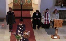 auf einem roten Läufer ist ein Weg angedeutet: Mit lila Tüchern, Fußspuren, Kerzen und Gegenständen aus dem Alltag