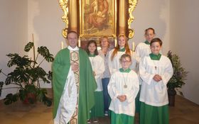 Pfarrer in einem grünen Meßgewand plus 5 Ministranten im Meßgewand im Altarraum einer Kirche