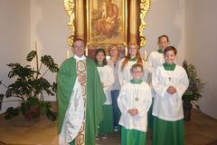 Pfarrer in einem grünen Meßgewand plus 5 Ministranten im Meßgewand im Altarraum einer Kirche