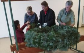 vier Frauen binden einen sehr großen Adventskranz
