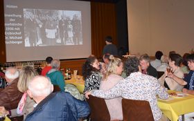 Besucher schauen auf eine Leinwand auf der historische Bilder gezeigt werden.