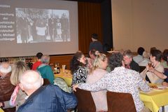 Besucher schauen auf eine Leinwand auf der historische Bilder gezeigt werden.