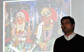 Kaplan Raveendra vor einem Bild mit Personen aus Indien