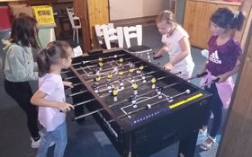 Vier Kinder um einen Kickertisch