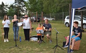 5 Personen im Halbkreis auf einer Wiese mit Instrumenten