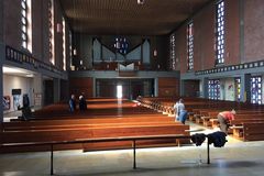 großer Kirchenraum mit vielen leeren Holzbänken, ein paar Erwachsene mit Besen und Lappen stehen im Bild