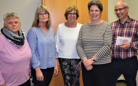 stehend vier Frauen und ein Mann, der ein Kuvert in der Hand hält