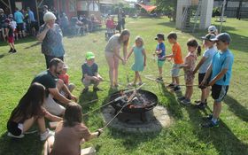 Kinder stehen um eine Feuerschale und halten ein Stockbrot in der Hand