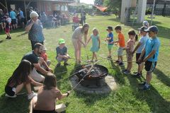 Kinder stehen um eine Feuerschale und halten ein Stockbrot in der Hand