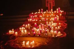 Kerzen läuchten auf rot-gelben-Tüchern vor einem Taizekreuz in der Dunkelheit
