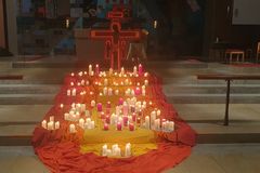 Kerzen auf rot-gelben-Tüchern vor einem Taize-Kreuz